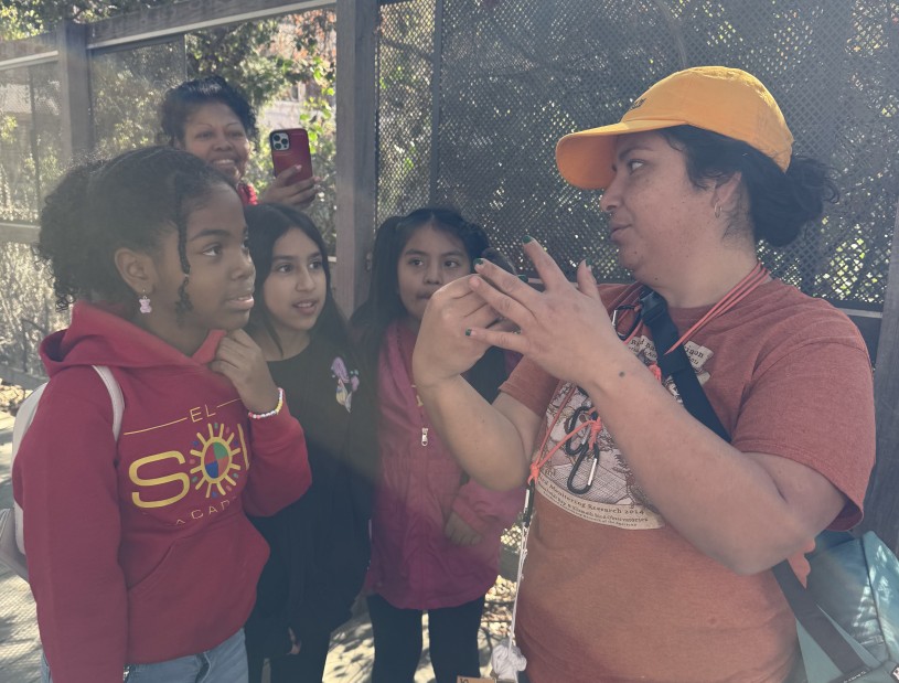 A researcher talks to three children visiting the Nature Gardens while their mother records